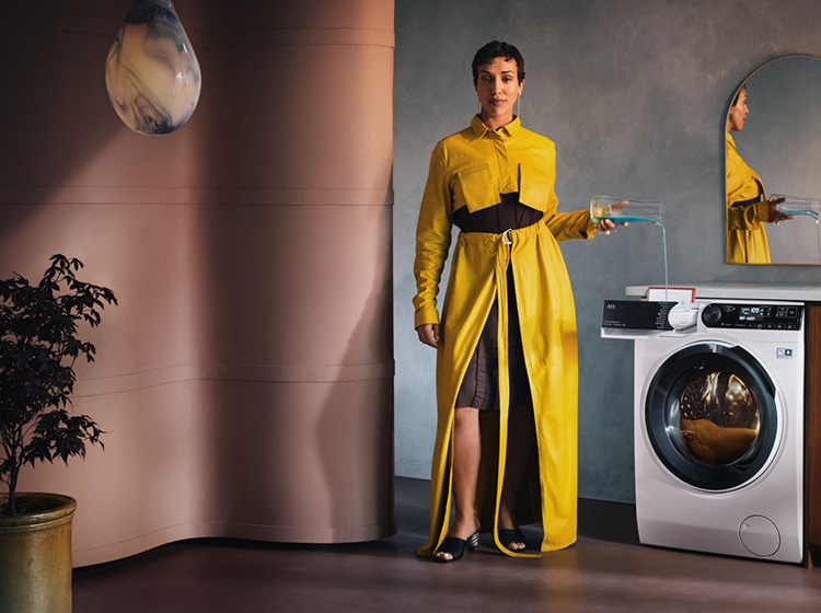 women standing next to an aeg washing machine.