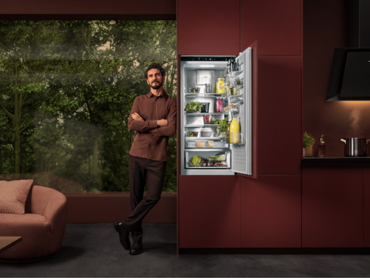 Man standing next to fridge in a kitchen.